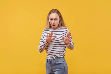 Ağzı açık, korkmuş sarışın bir kadın. Sarı arkaplan.