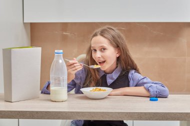 Tatlı kız sabahları kahvaltıda mısır gevreği ve süt yiyor..