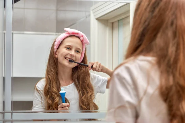 Блондинка с длинными волосами чистит зубы в ванной. — стоковое фото