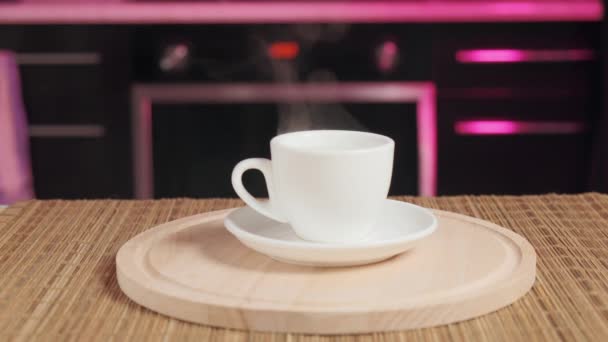 Sur un plateau en bois est une tasse de café parfumé. La cuisine est en arrière-plan. — Video