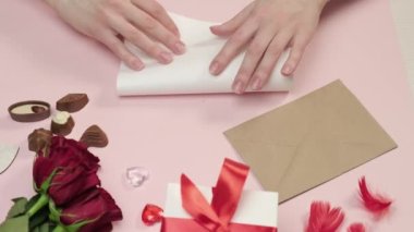 Bir kadın el, bir zarf içinde kağıda bir aşk mektubu düzenler. Bir buket gül..