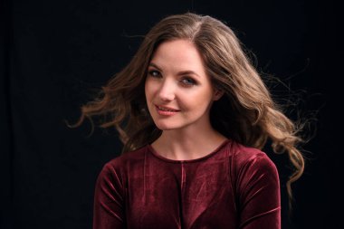 Uzun ve sağlıklı dalgalı saçlı güzel esmer bir kadın kameraya bakar..