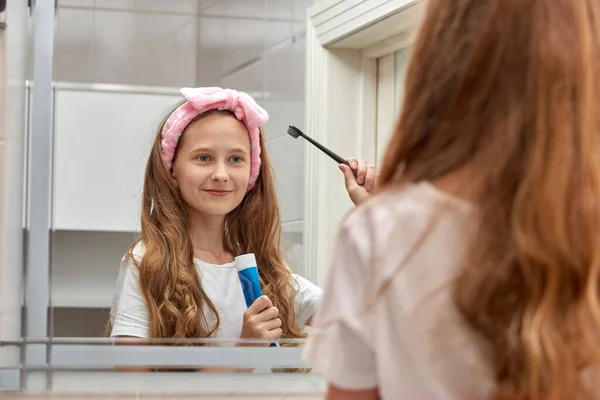 Блондинка-подросток в ванной чистит зубы. Уход за полостью рта. — стоковое фото