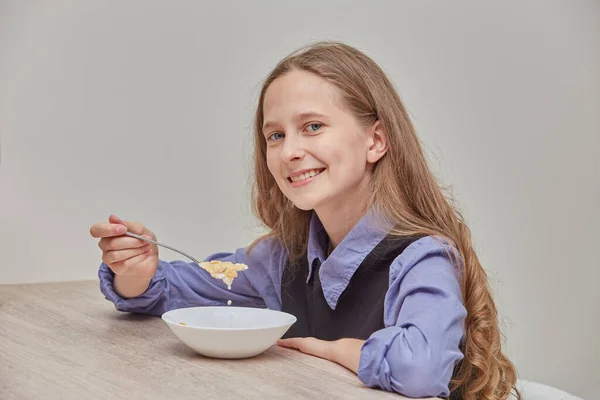 テーブルで朝にミルクとコーンフレークを食べる美しい女の子. — ストック写真