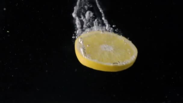 Шматочок лимона падає у воду зверху вниз. Поняття соку . — стокове відео