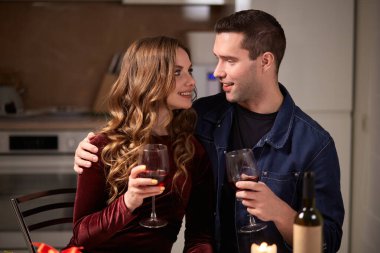 Karı koca mutfakta sarmaş dolaş şarap içiyorlar. Sevgililer Günü.