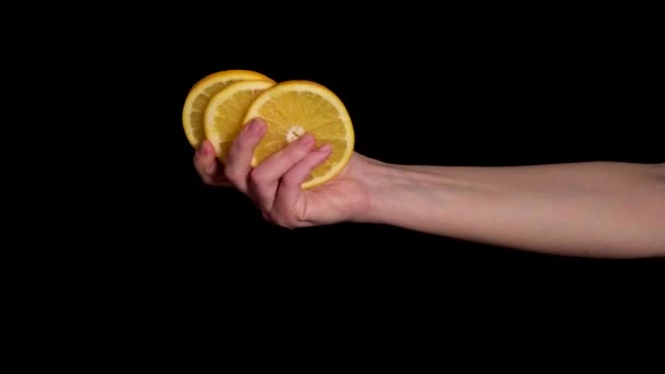 Egy női kéz három szelet érett narancsot tart a kezében. 4k videó. — Stock videók