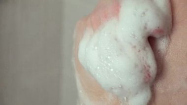 Bir kadın çıplak omzunu köpükle yıkar..