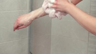 Genç bir kadın elini bir bez ve sabunla yıkıyor. Bol köpüklü..