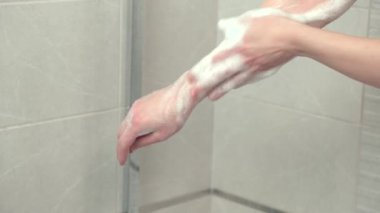 Genç bir kadın ellerini yıkıyor, sabun ve duş jeli yıkıyor, bol köpüklü..