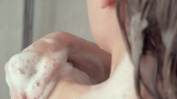 Genç bir kadın banyoda çıplak omzunu köpükle yıkıyor.. — Stok video