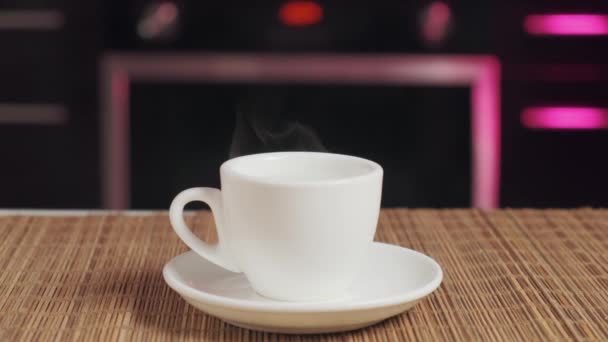 Sur un plateau en bois est une tasse de café blanc, avec une tasse de vapeur blanche. — Video