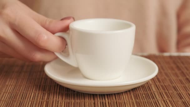 Main d'une femme buvant du café avec une tasse en céramique blanche dans un café. — Video