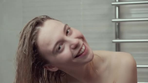 Seorang wanita muda yang cantik di kamar mandi putih menerapkan masker rambut untuk rambut basah dicuci. — Stok Video