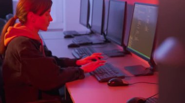 Ofiste çalışan genç ve güzel bir programcı. Karanlık bir odada pembe ışık.