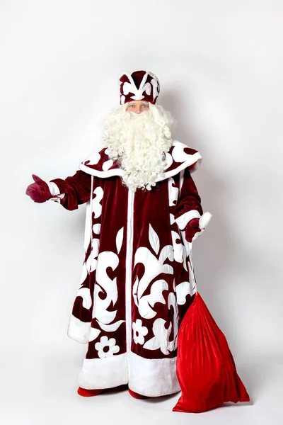 Ein Mann im Weihnachtsmann-Kostüm, Ded Moroz winkt mit der Hand und hält eine Tüte Geschenke in der Hand. — Stockfoto