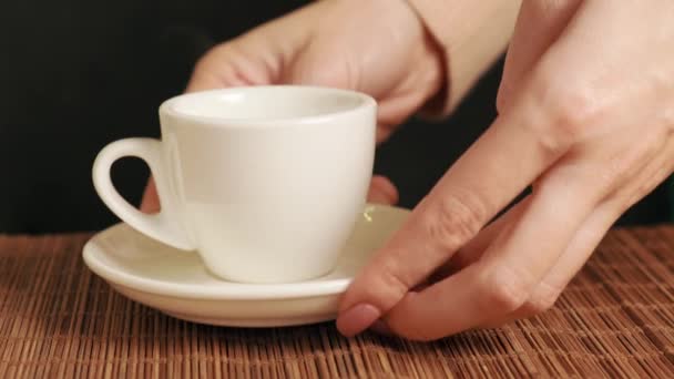 En kvinna lägger en vit väldoftande kaffekopp på bordet. — Stockvideo