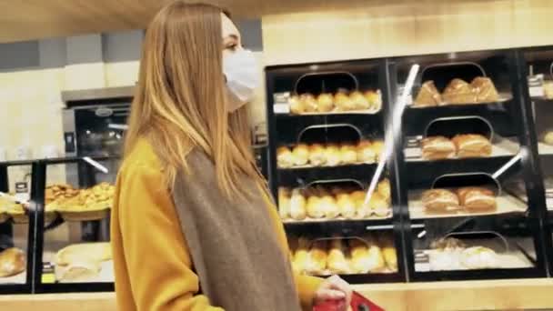 Bir kadın perakende mağazasında maske takarak yemek reyonunda yürüyor.. — Stok video