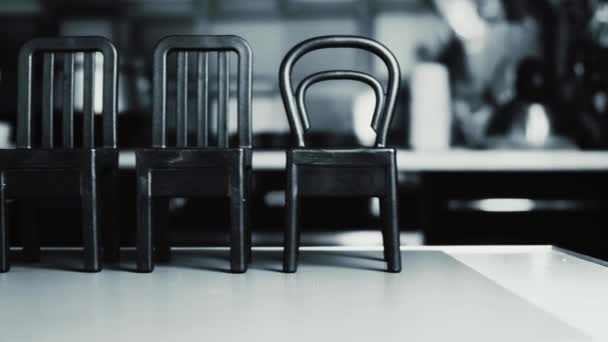 Черно-белое видео с четырьмя серыми стульями справа налево. — стоковое видео