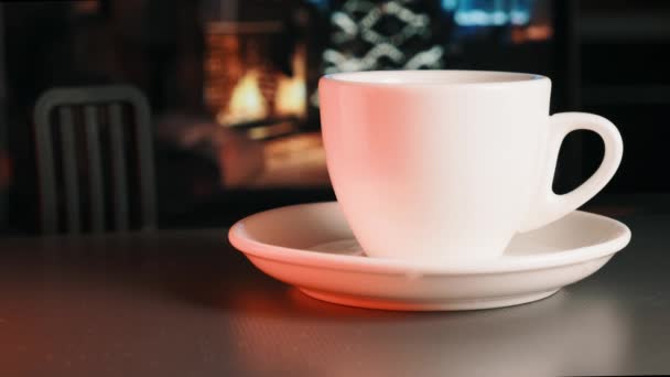 テーブルの上にはカップがあり、香りがあります。暖炉が点灯します. — ストック動画