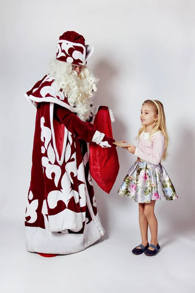 Uma menina em uma saia elegante recebe um presente do Papai Noel na véspera de Natal. — Fotografia de Stock