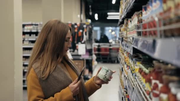 Genç bir kadın fiyat etiketini bulmak için bir ürünün barkodunu tarıyor.. — Stok video