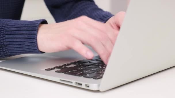 Un hombre trabaja en una oficina en un portátil. Imprime texto en el teclado del portátil. — Vídeos de Stock