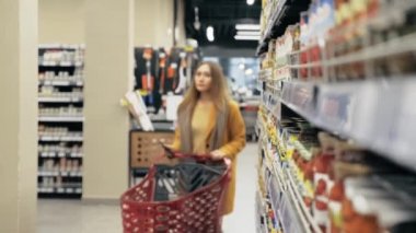 Genç bir kadın ürünün barkodunu tarayıp el arabasına koyuyor..
