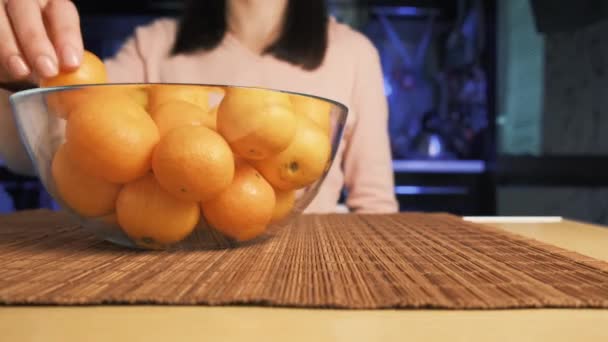 Kobieta umieszcza dojrzałe soczyste mandarynki w przezroczystej szklanej płytce. — Wideo stockowe