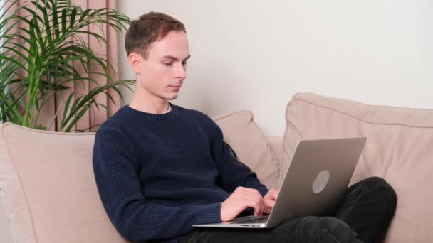 Homme travaillant en ligne à la maison assis sur le canapé. Travailler en tant que pigiste en ligne. — Video