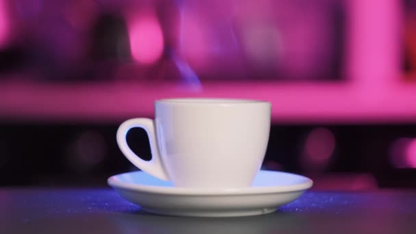 En la mesa hay una taza blanca y hay el aroma del café, vapor blanco. — Vídeo de stock