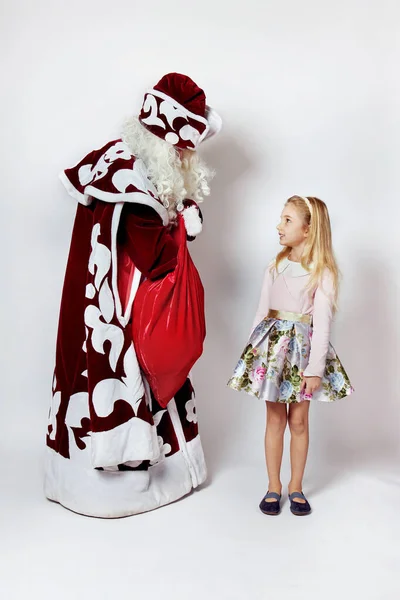 Papai Noel tira um presente para uma menina no Natal de um saco vermelho. — Fotografia de Stock