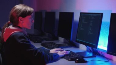 Bilgisayarda çalışan genç bir kadın programcı. Mavi ve kırmızı arka plan.