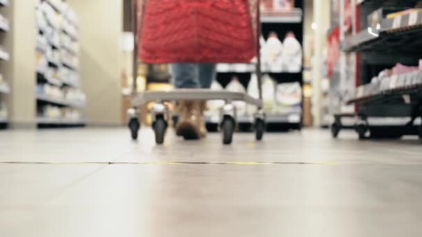 Μια θολή εικόνα, μια νεαρή γυναίκα με καρότσι για ψώνια, σταματάει κοντά στη γραμμή του στοπ.. — Αρχείο Βίντεο