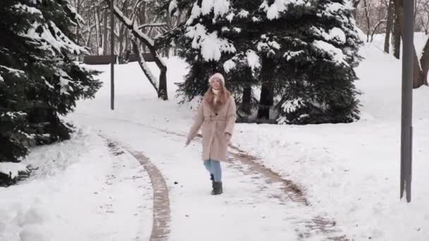 베이지 코트를 입고 눈덮인 도로에서 춤을 추는 아름다운 아가씨. — 비디오