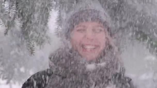 Retrato de uma jovem mulher em quem a neve cai de um ramo de cima. — Vídeo de Stock