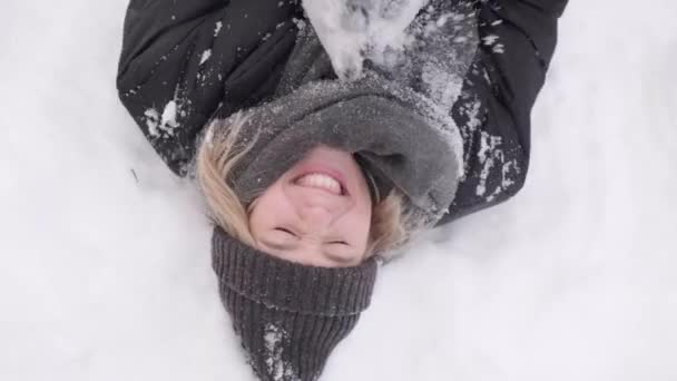 눈 위에 누워 있는 한 여인의 맨 위에 있는 모습. 겨울 놀이를 하는 여자. — 비디오