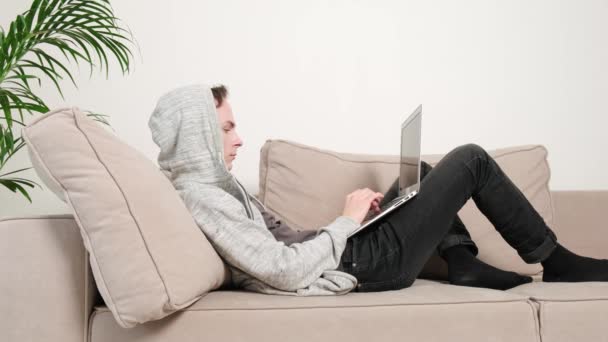 Un homme est allongé sur le canapé, travaille en ligne et ferme les yeux et l'ordinateur portable. — Video