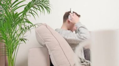 Genç bir erkek serbest yazar, dizüstü bilgisayarında beyaz kulaklıklarla yazı yazıyor..