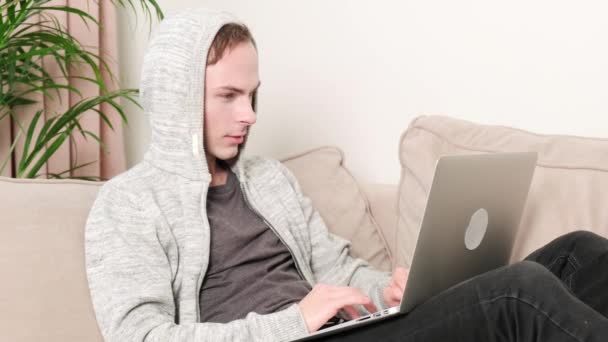 Een man typt thuis op een laptop en is blij met succes of winnen. — Stockvideo