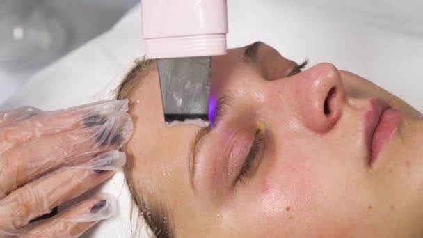 Detergere il viso di una bella donna con peeling a cavitazione ultrasonica. — Video Stock