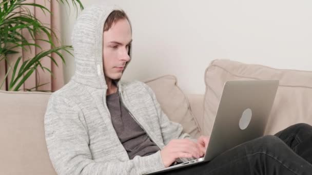 Um homem está digitando texto em casa em um laptop, feliz e feliz com um trabalho bem feito. — Vídeo de Stock