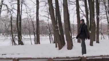 Genç ve güzel bir kadın kışın tahta bir köprüde yürür. Karlı soğuk kış.