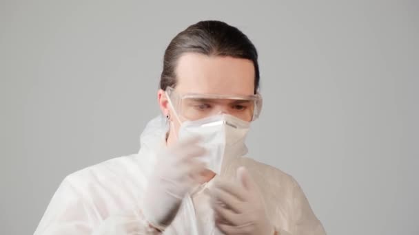 Un hombre con el pelo largo se pone un traje químico de protección médica.. — Vídeos de Stock