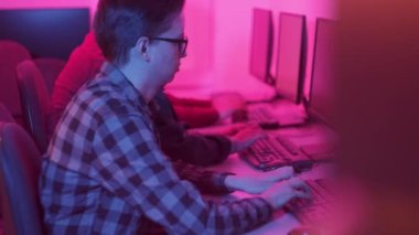 İki gömlekli adam akşamları ofiste çalışıyor. Parlak pembe ışık.