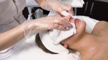 Kozmetik uzmanı güzellik salonunda müşterilerin yüzünü peçetelerle temizler..