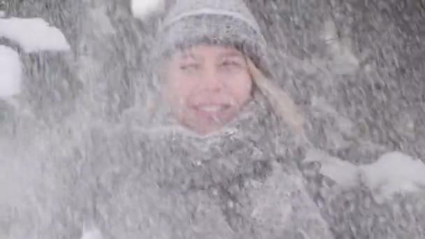 Filmagem em câmera lenta de neve caindo sobre uma mulher jovem, feliz e sorridente. — Vídeo de Stock