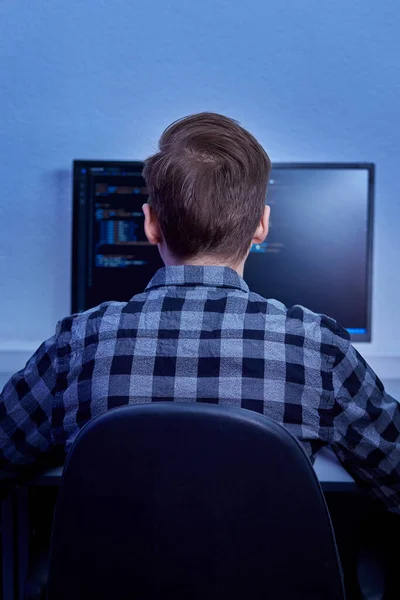 Ekose gömlekli genç bir erkek programcının arkadan görünüşü..