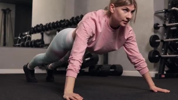 Uma jovem faz flexões do chão. Corpo atlético. — Vídeo de Stock