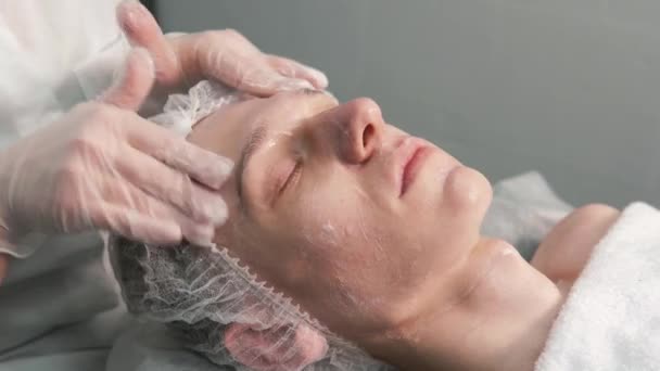 Kosmetolog masíruje obličej mladému muži. Kosmetický salon. — Stock video